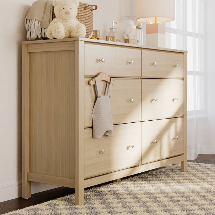 a teddy bear sitting on top of a wooden dresser