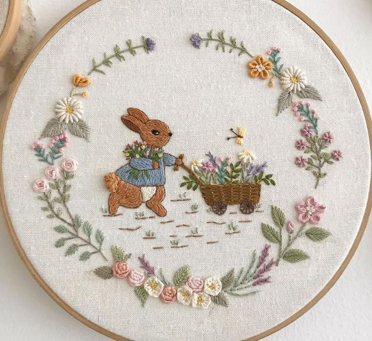 a cross stitch pattern with a bunny pushing a wheelbarrow filled with flowers