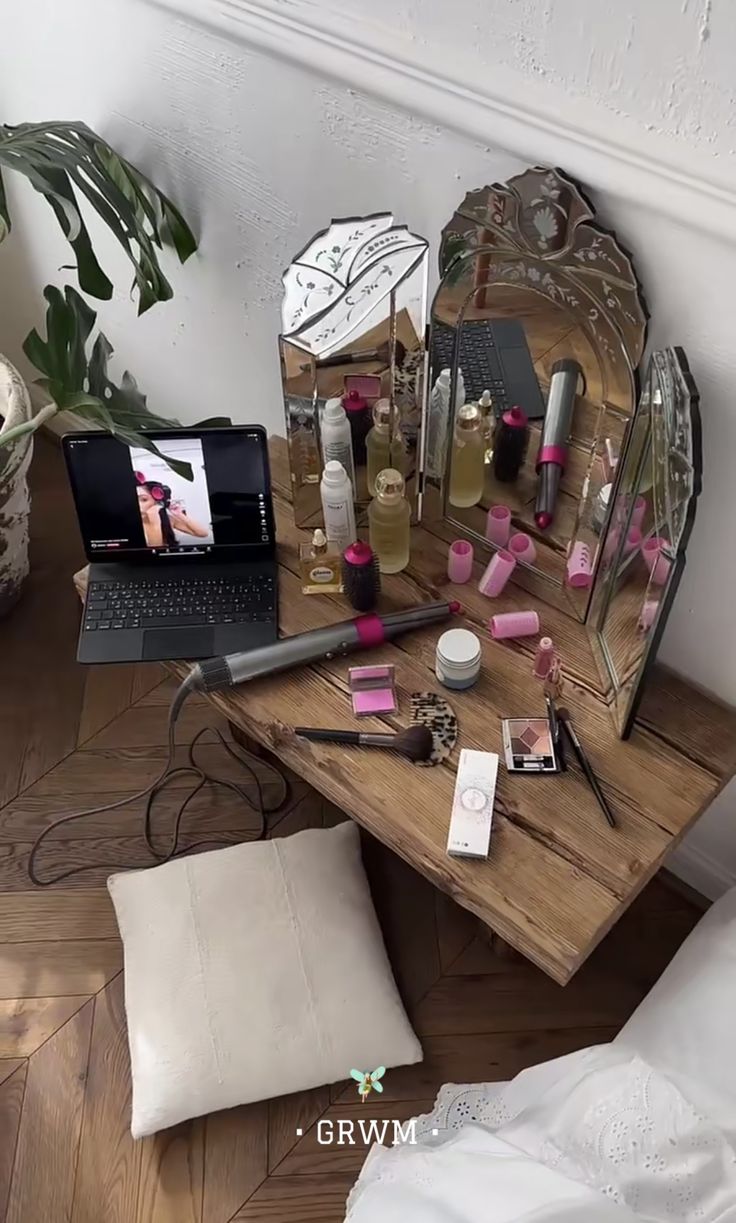 a desk with a laptop, mirror and other items on it