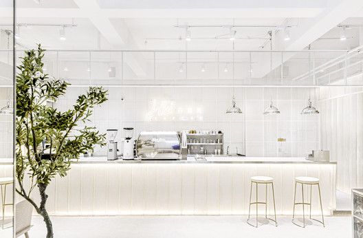 the interior of a modern restaurant with white walls and flooring is lit by recessed lights