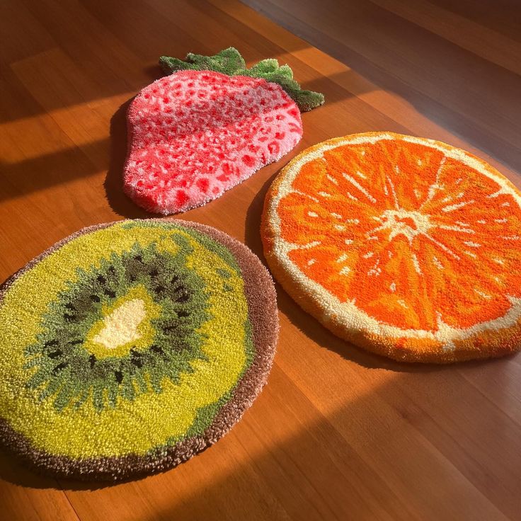 three fruit shaped rugs sitting on top of a wooden table