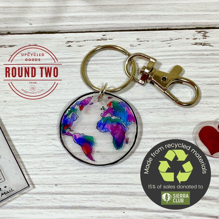 a keychain with a world map on it and a recyclist badge next to it