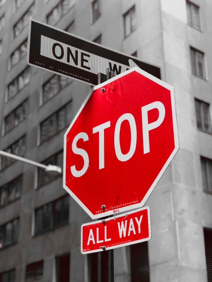 a red stop sign sitting on the side of a road next to a tall building