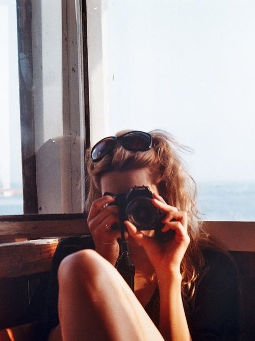 black and white photograph of a woman sitting in front of a window with her camera