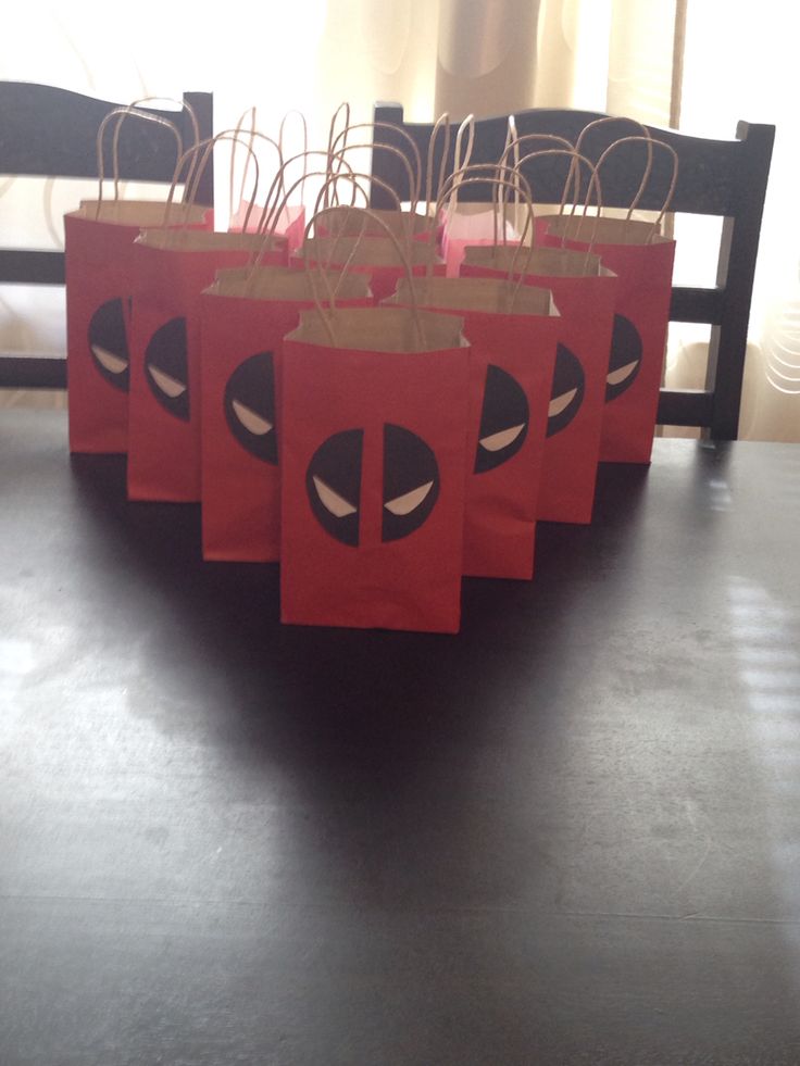 red paper bags with black faces on them sitting on a table in front of a window