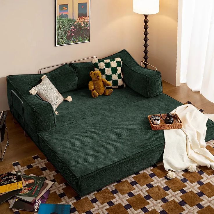 a green couch sitting on top of a wooden floor in a living room next to a lamp