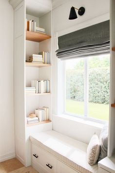 a window seat in front of a bookshelf filled with books