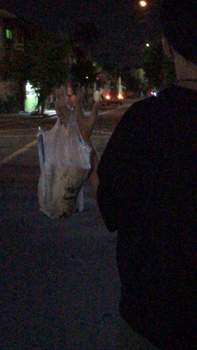 a woman is walking down the street at night with her hand up in the air