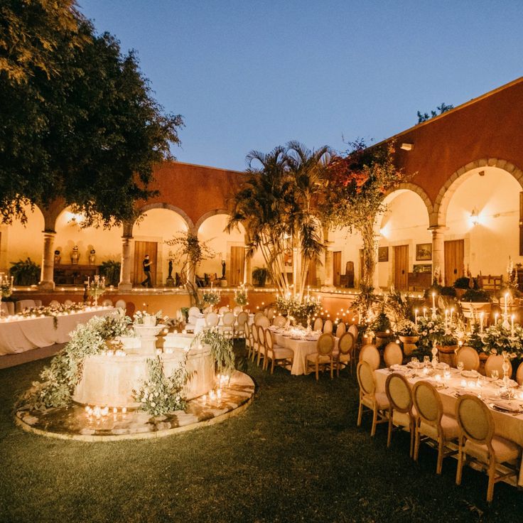 an outdoor dining area with tables and chairs set up for formal function at night time