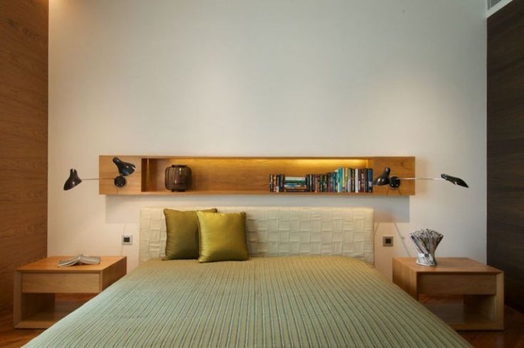 the bed is made up and has two nightstands on each side with bookshelves above it