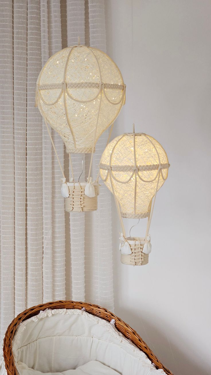 two hot air balloons suspended from the ceiling above a wicker basket on a bed