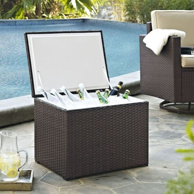 an open cooler sitting on top of a patio next to a swimming pool with drinks in it