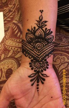 a woman's hand with a black henna tattoo on her arm and wrist