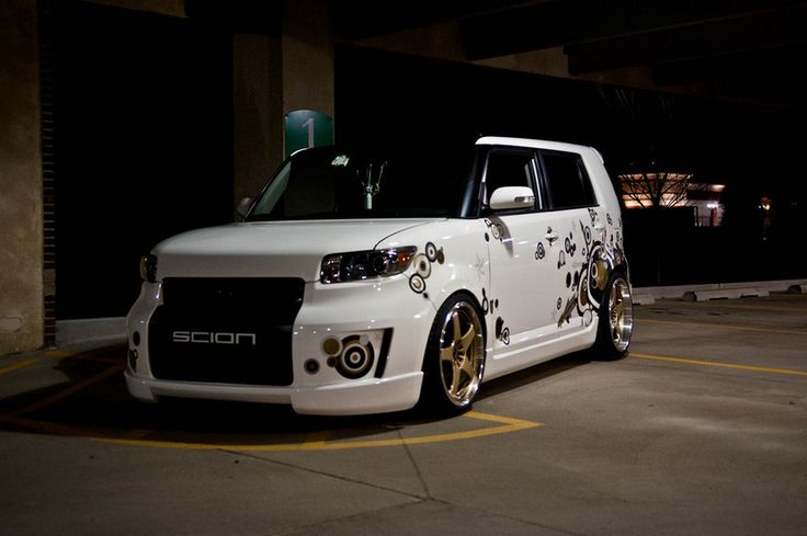 a white car with gold rims parked in a parking lot