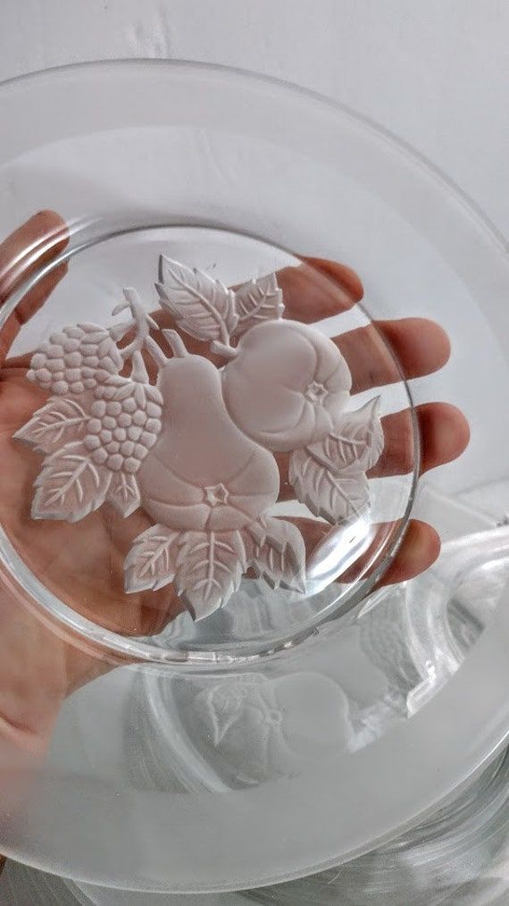 a person is holding a glass plate with flowers on it