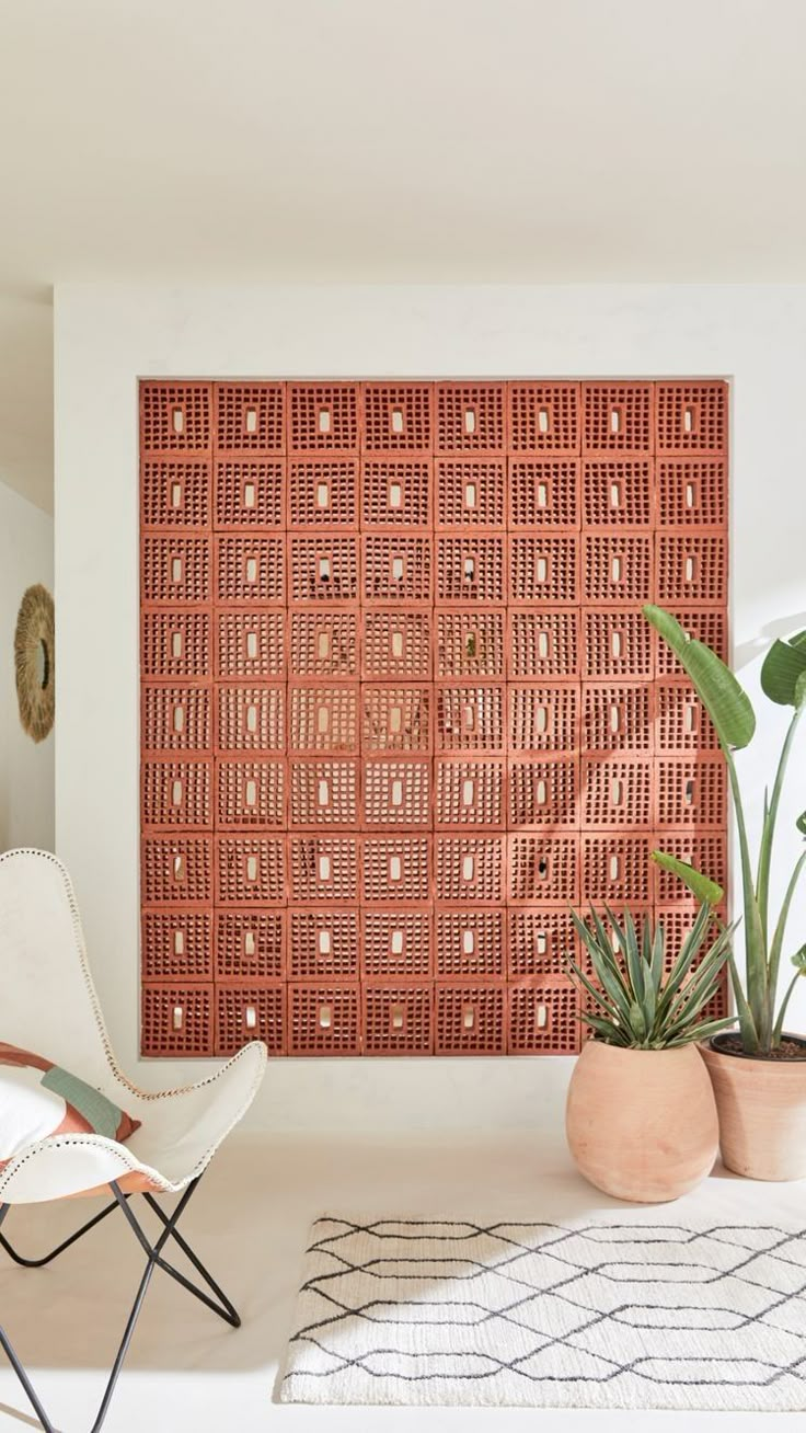 a living room with two plants and a wall hanging