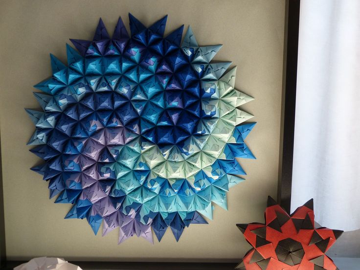 two origami pieces are sitting next to each other in front of a wall decoration