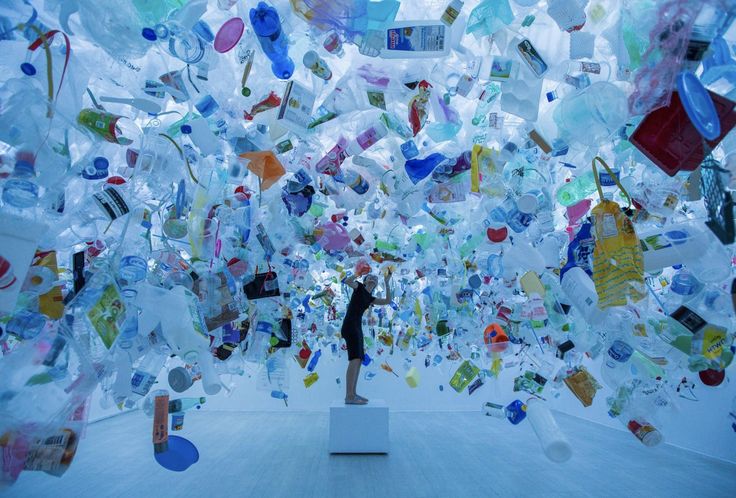 a person standing in front of a large amount of glass bottles hanging from the ceiling