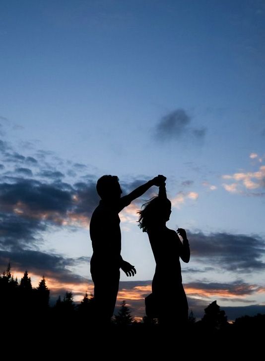 two people are silhouetted against the evening sky