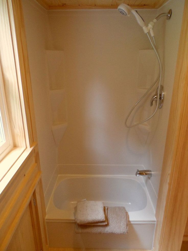 a bath tub sitting inside of a bathroom next to a shower head mounted on the wall