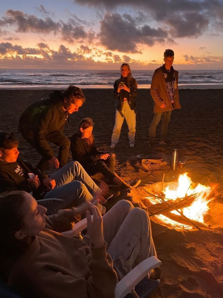 people sitting around a campfire on the beach