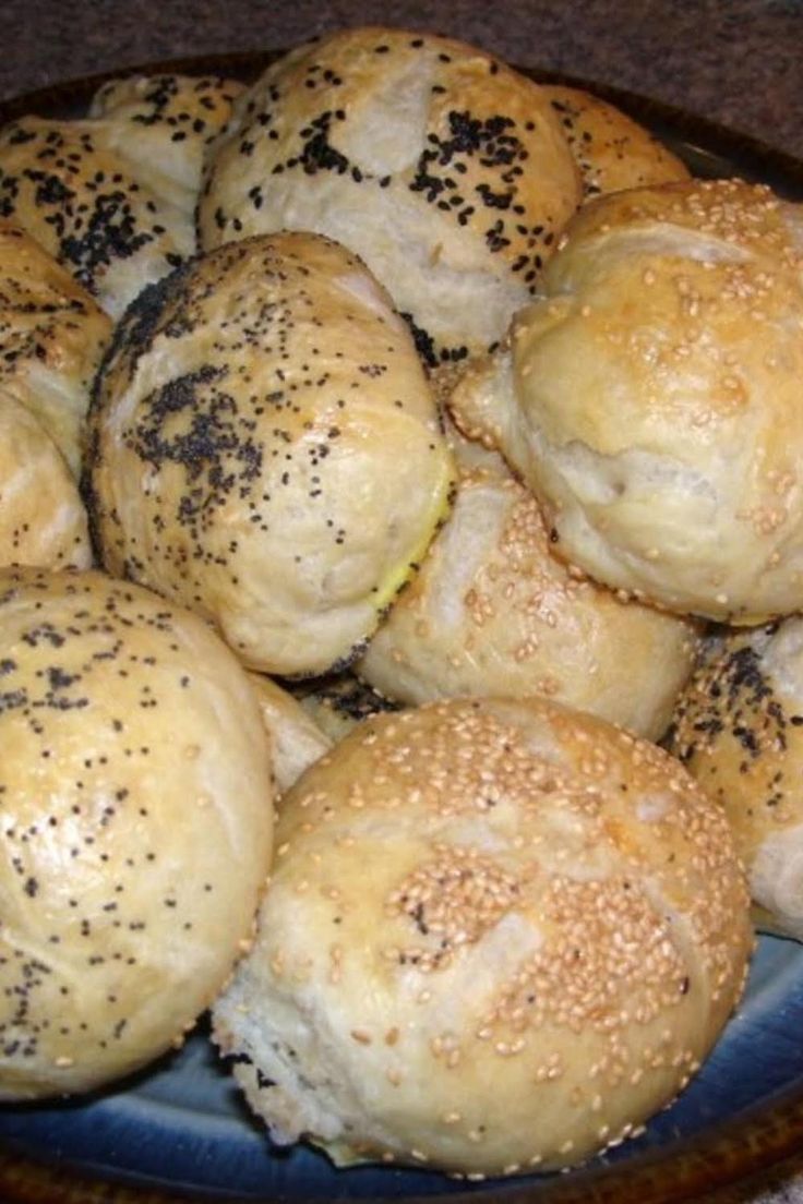 a blue plate filled with rolls covered in sesame seeds and sprinkled with black pepper