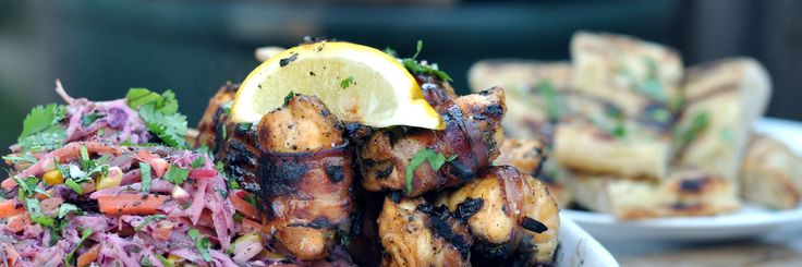 grilled chicken, coleslaw and lemon wedges are served on white plates