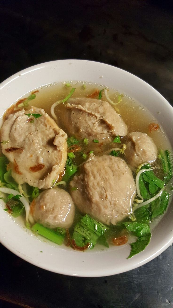 a white bowl filled with meatballs and veggies on top of a table