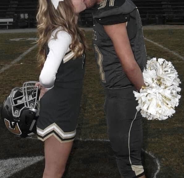 a couple of people that are standing in the grass with cheerleader's uniform