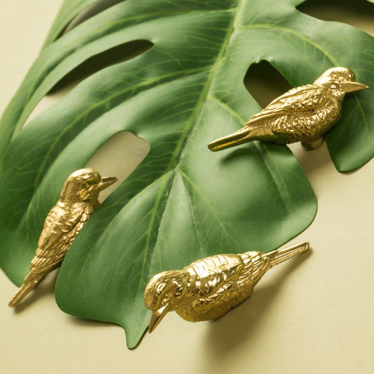 two gold birds sitting on top of a green leaf