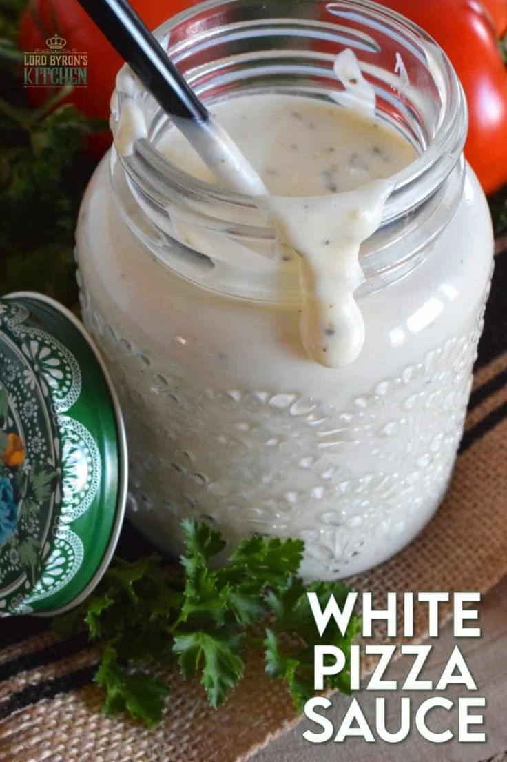 white pizza sauce in a mason jar with parsley on the side and tomatoes behind it