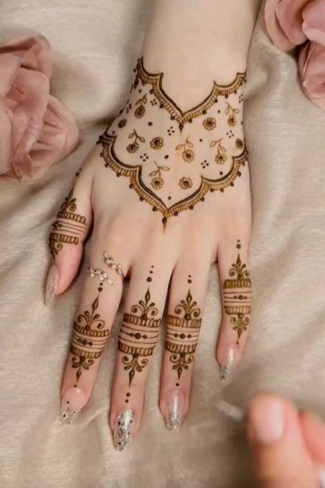 a woman's hands with hennap on top of her hand and flowers in the background