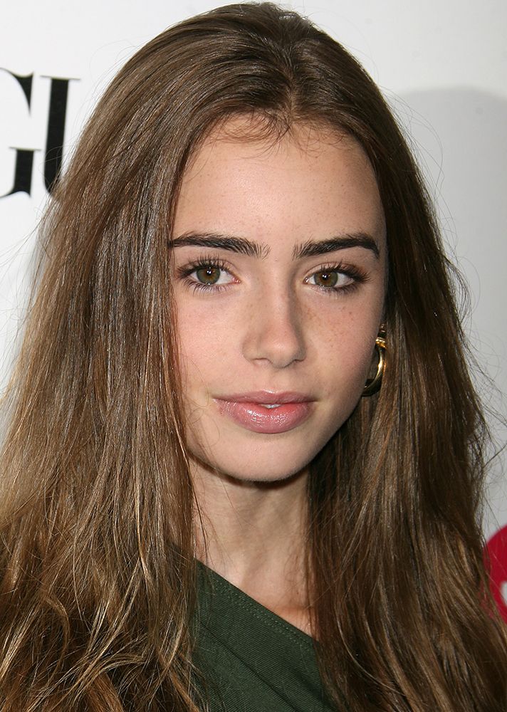 a close up of a person with long hair and earrings on her head, wearing a green shirt