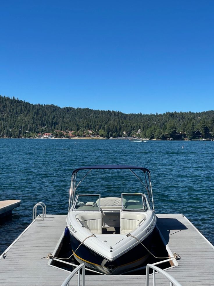 a boat is docked at the end of a dock with trees in the background on a sunny day