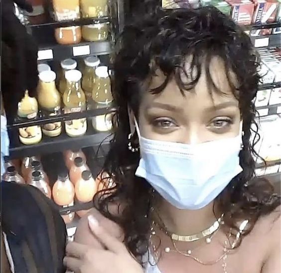 a woman wearing a face mask while standing in front of a grocery store display case