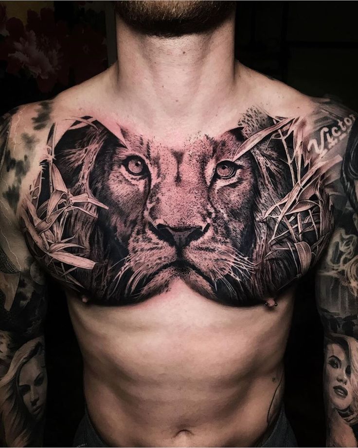 a man with tattoos on his chest and chest is wearing a lion face tattoo design