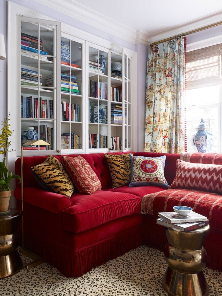 a living room with a red couch and bookshelf in the corner, next to a coffee table