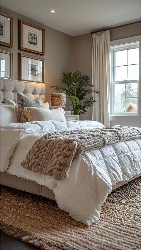 a large bed sitting in the middle of a bedroom next to a window with two framed pictures on it