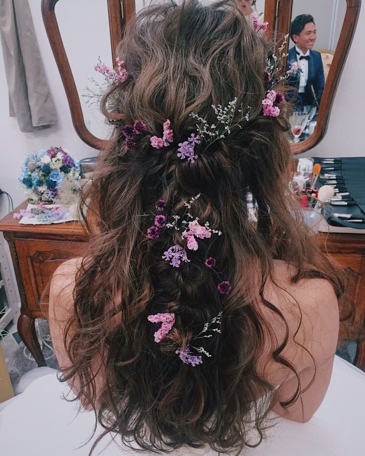 the back of a woman's head with flowers in her hair, sitting on a chair