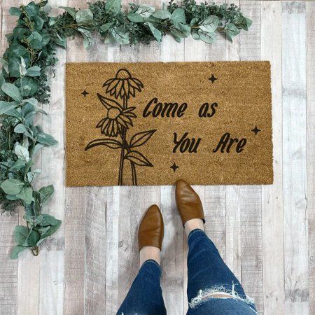 someone standing in front of a door mat that says come as you are