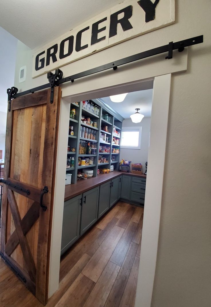 an open door leading into a kitchen with wooden floors and shelves on either side of it