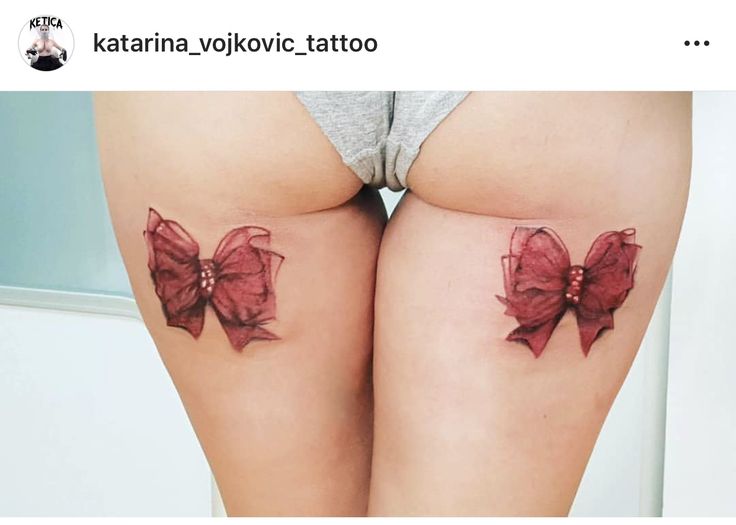 two women with tattoos on their butts and one has a red bow in it