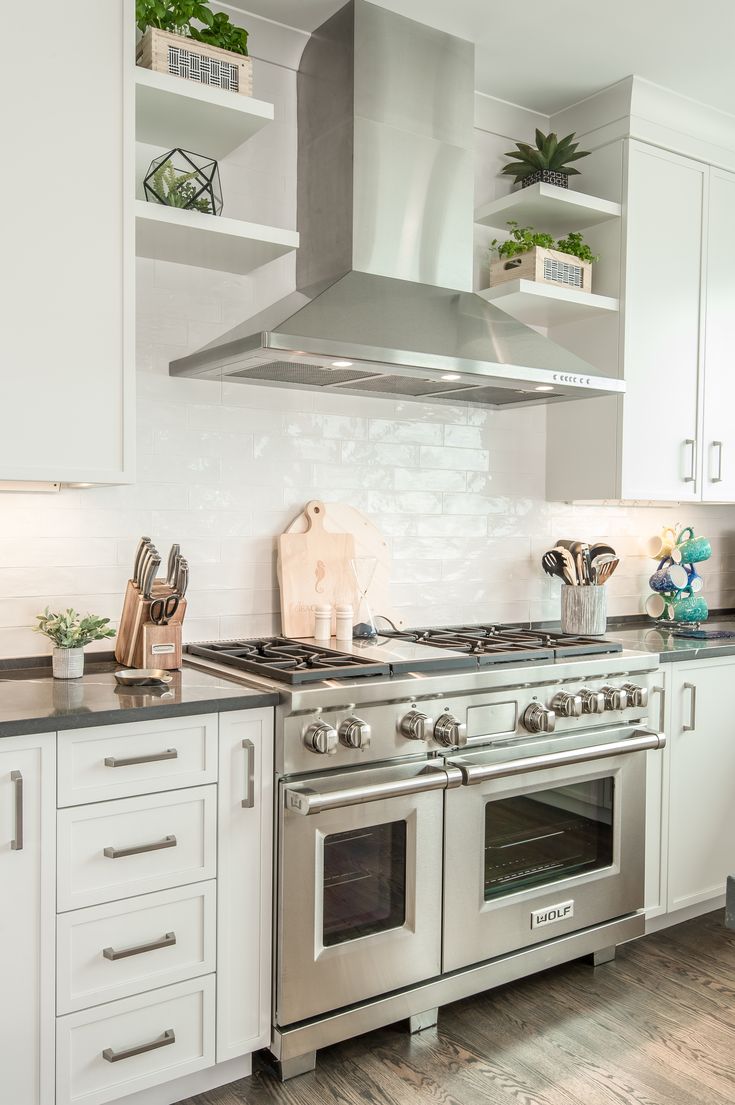 a stove top oven sitting inside of a kitchen next to white cabinets and counter tops