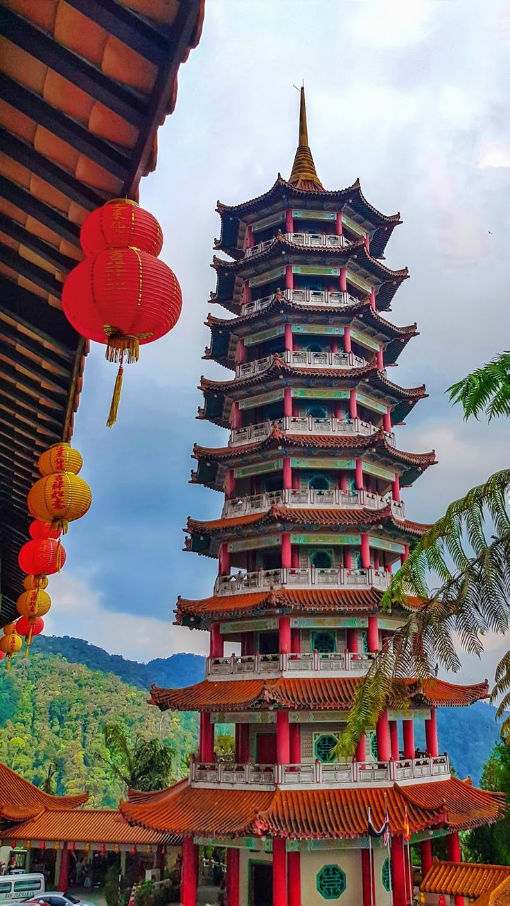 a tall building with red and yellow decorations hanging from it's sides in front of mountains