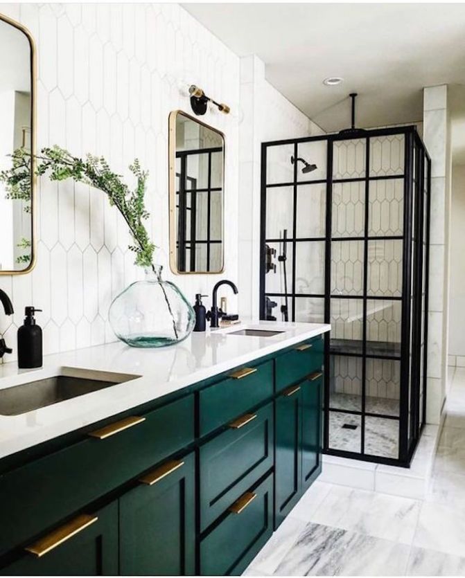 a bathroom with green cabinetry and marble counter tops, along with a white tiled wall