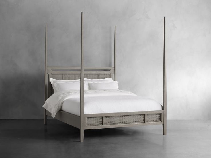 a bed with four posts and white linens in a room that is painted gray