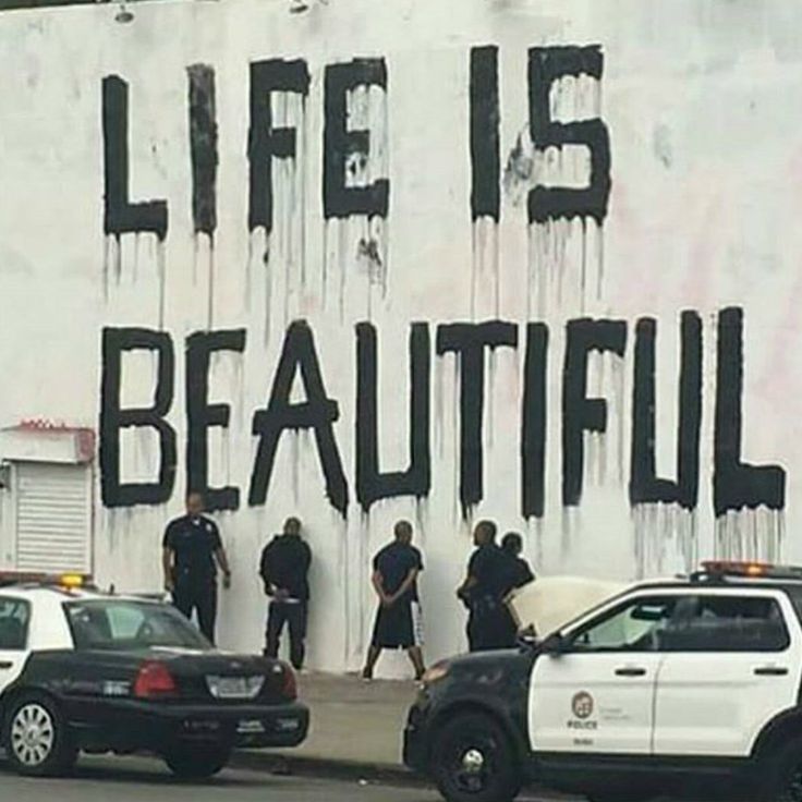 several police cars parked in front of a wall that says life is beautiful