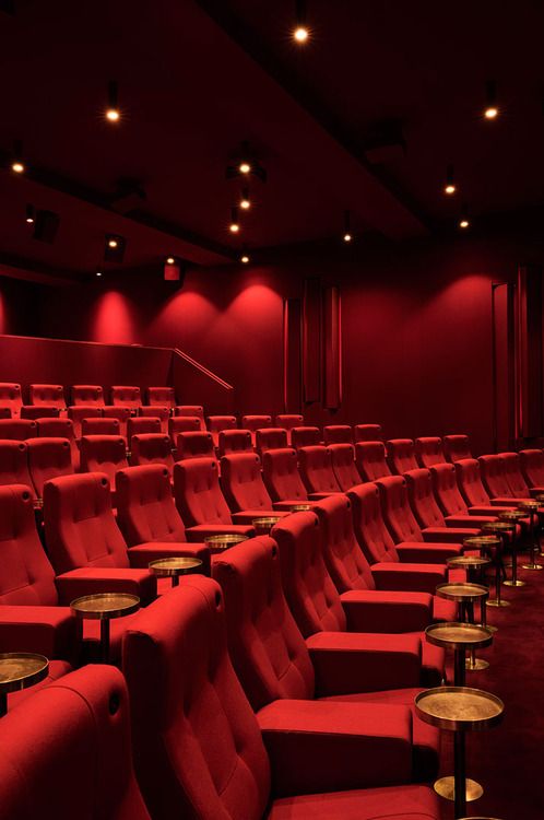 an empty theater with red chairs and tables