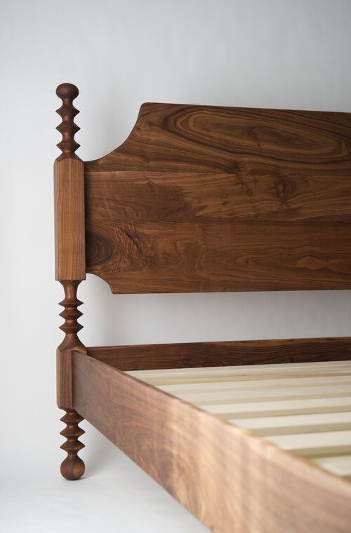 a wooden bed frame and headboard against a white wall