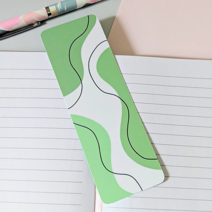 a notepad with a green and white design on it sitting next to a pen